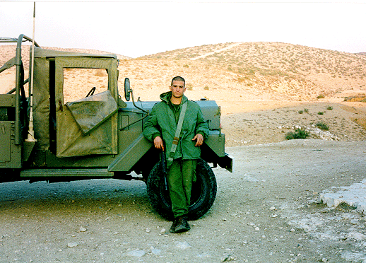 Yonatan standing before army truck